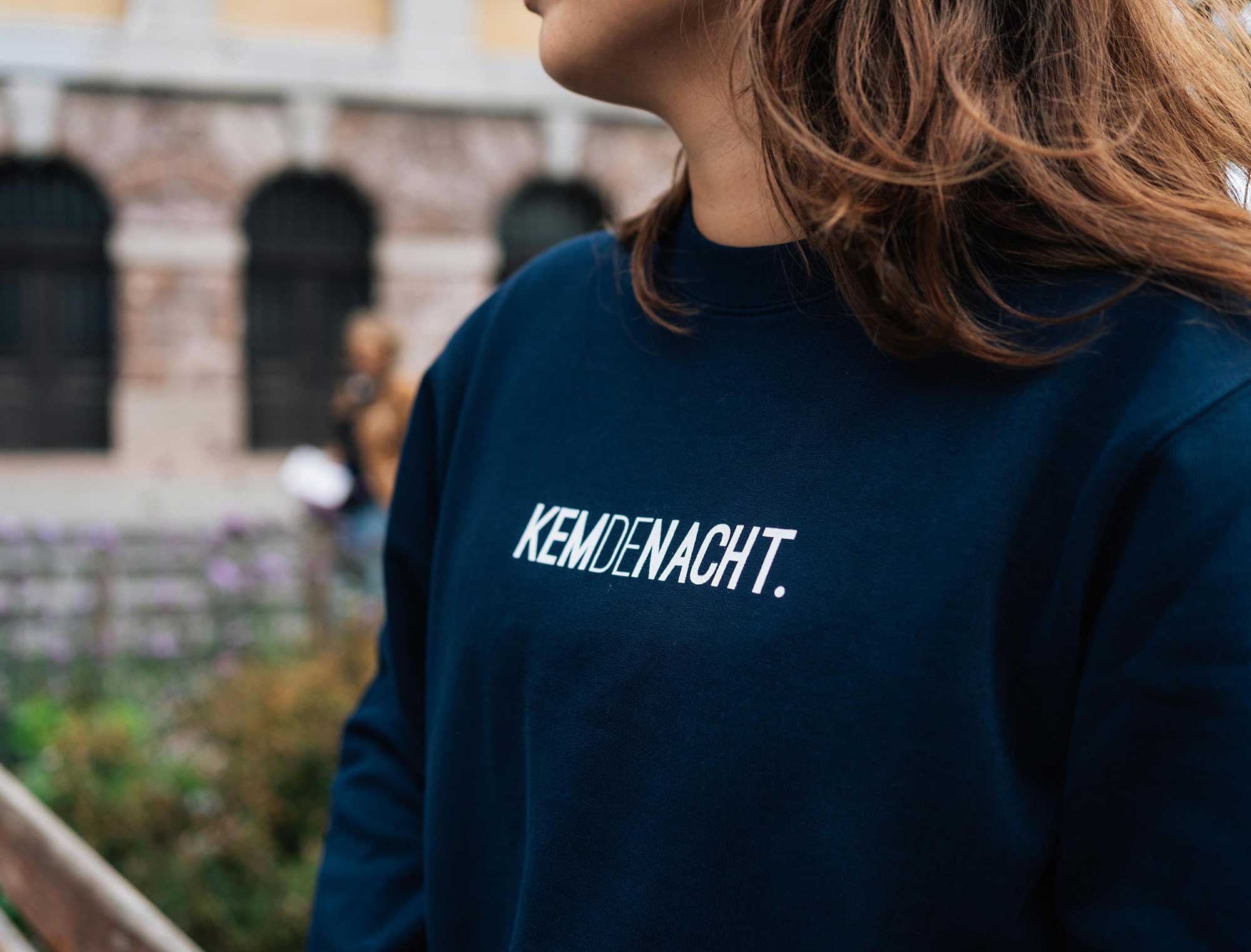 Close-up van een donkerblauwe sweater met opdruk KEMDENACHT.