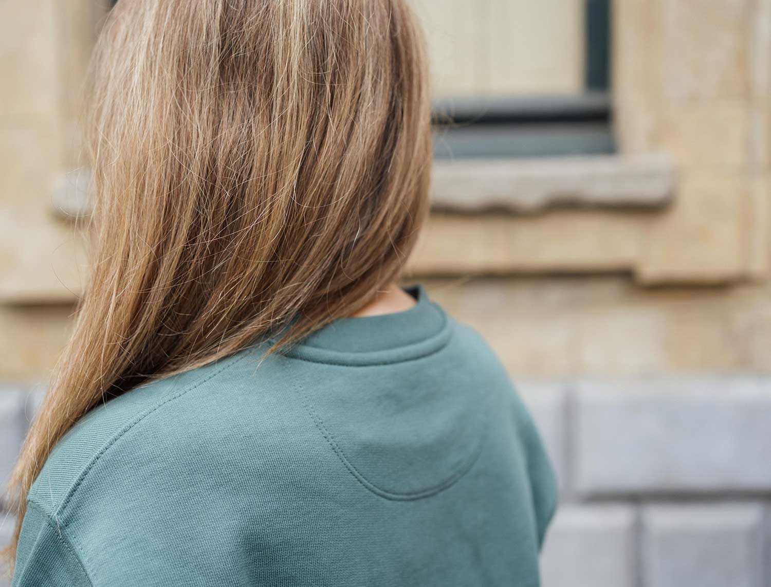 Achterkant van een groene sweater met opdruk KEMDEUST.