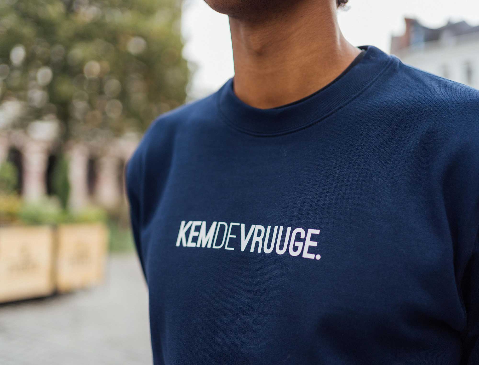 Close-up van een donkerblauwe sweater met opdruk KEMDEVRUUGE.