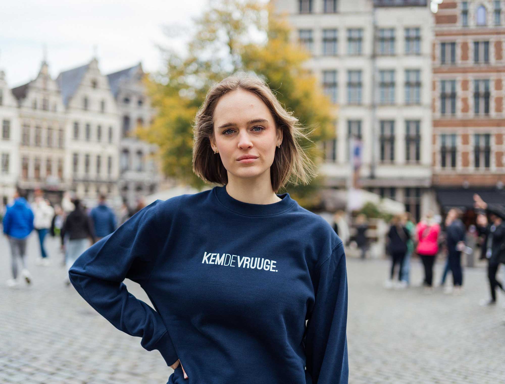 Vrouw met een donkerblauwe sweater met opdruk KEMDEVRUUGE.