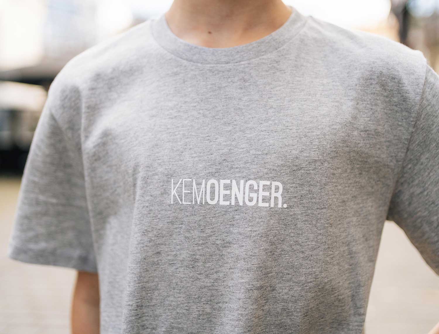 Close-up van grijze T-shirt met opdruk KEMOENGER.