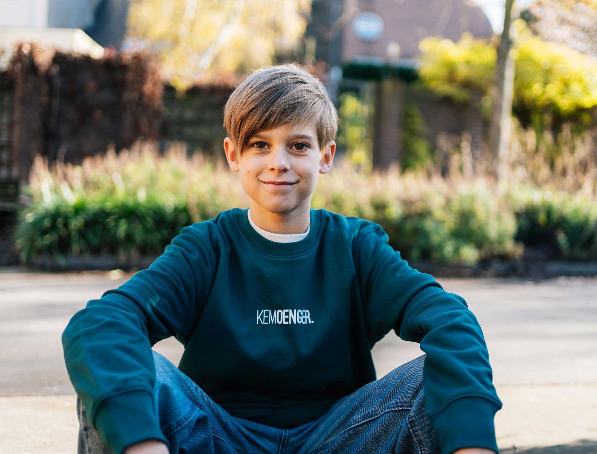 Jongen met een groene sweater voor kinderen met opdruk KEMOENGER.