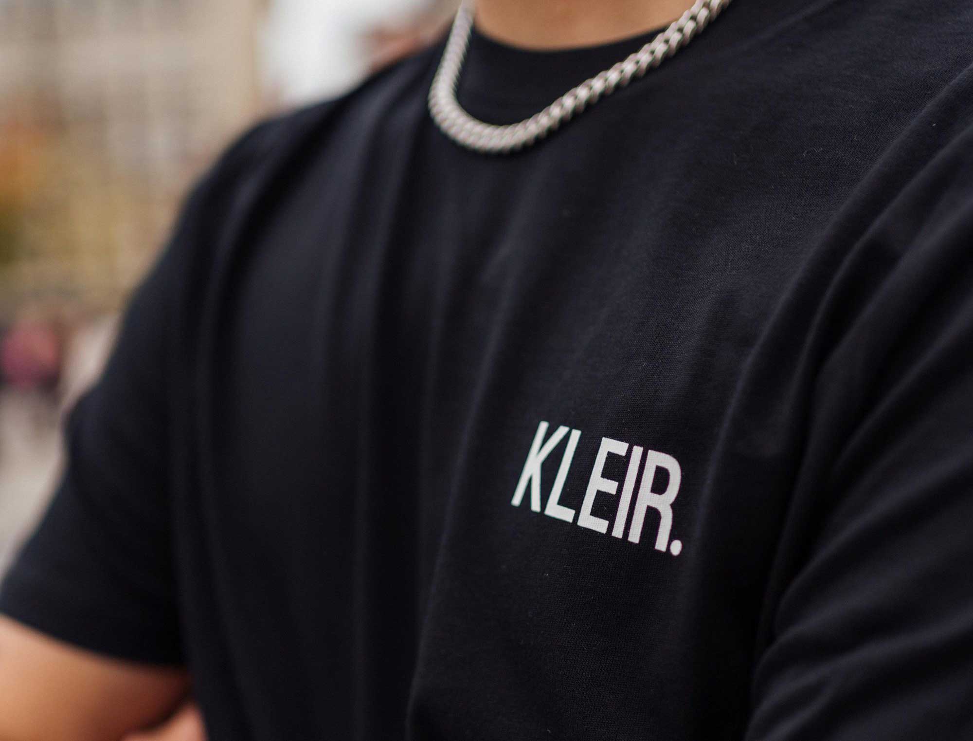 Close-up van een zwarte T-shirt met opdruk KLEIR.