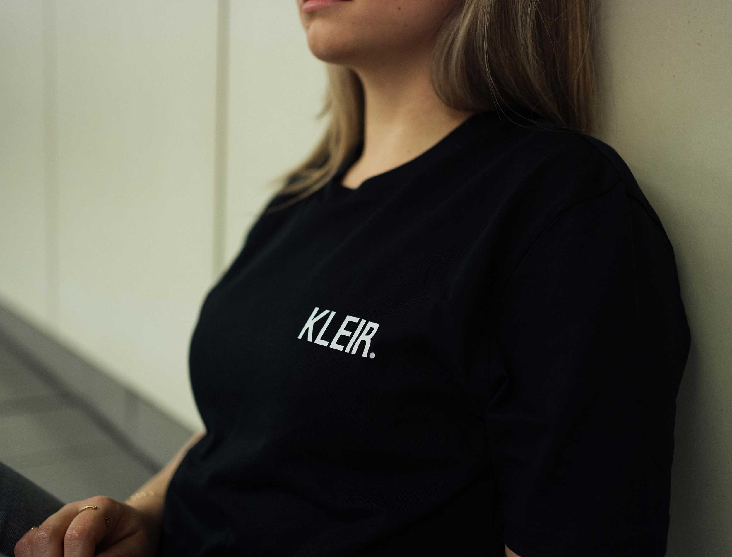 Close-up van een zwarte T-shirt met opdruk KLEIR.