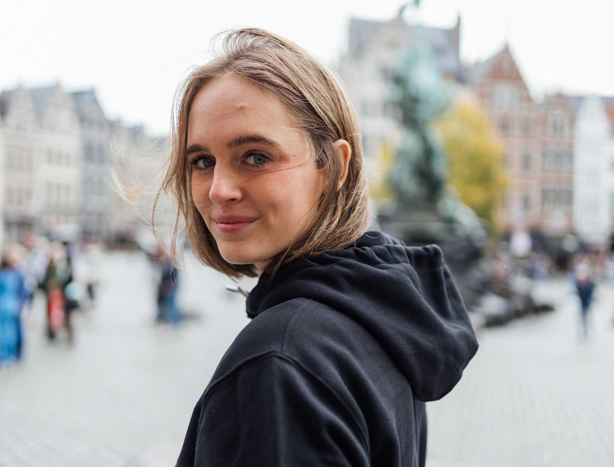 Zijkant van een vrouw met een zwarte hoodie met opdruk KLEIR.