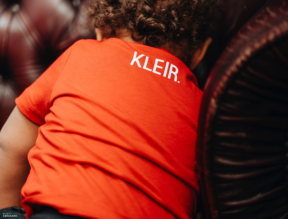 Close-up van een rode T-shirt met opdruk KLEIR. in de nek