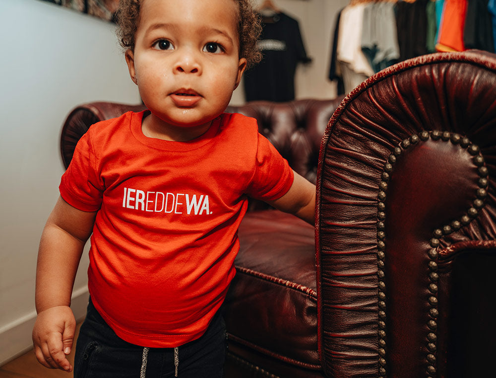Baby met rode T-shirt met opdruk IEREDDEWA.