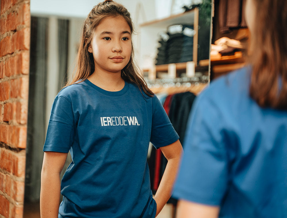Meisje met een blauwe T-shirt met opdruk IEREDDEWA.