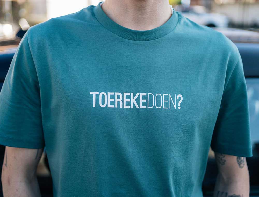 Close-up van een groene T-shirt met opdruk TOEREKEDOEN?