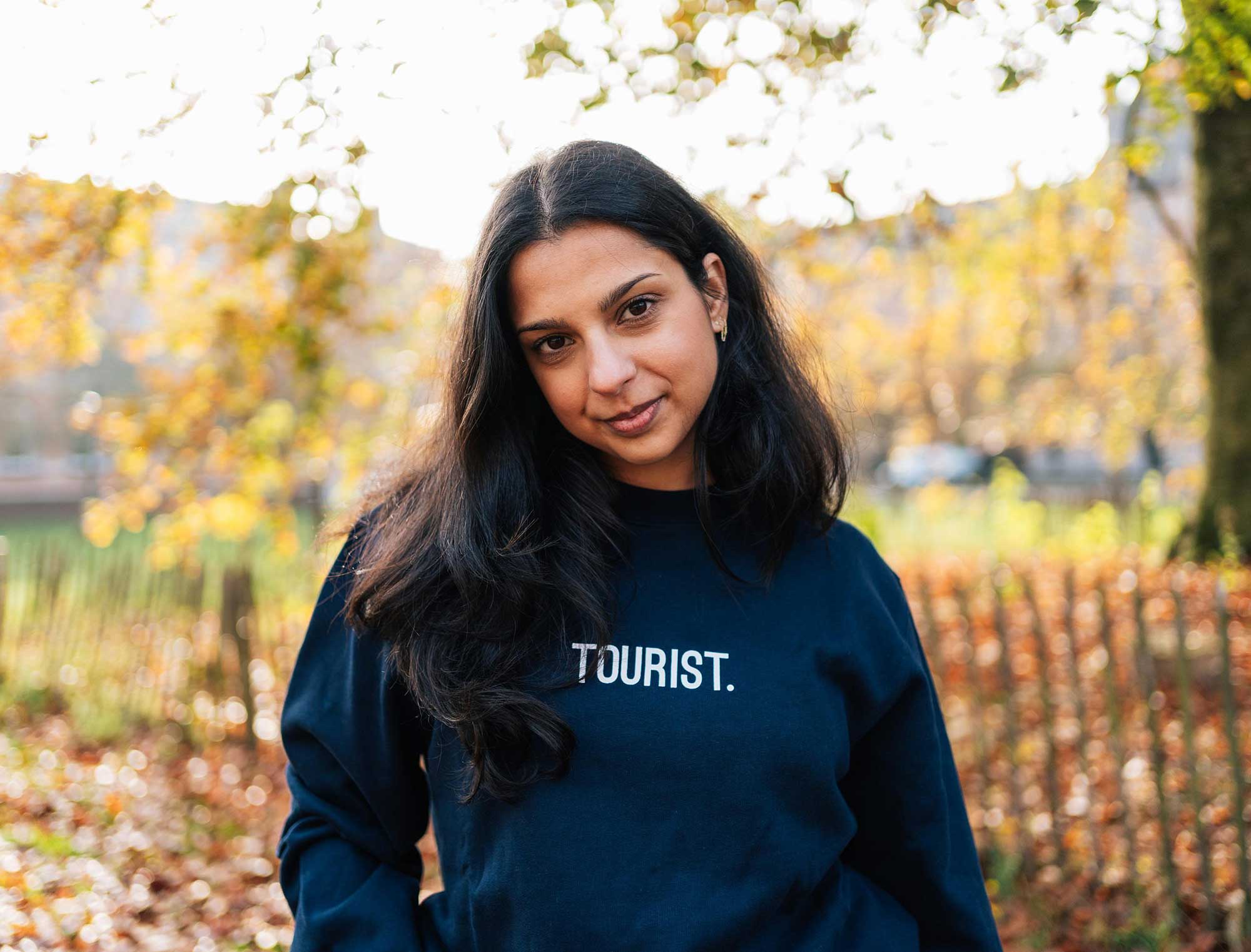 Vrouw met een donkerblauwe sweater met opdruk TOURIST. voor volwassenen