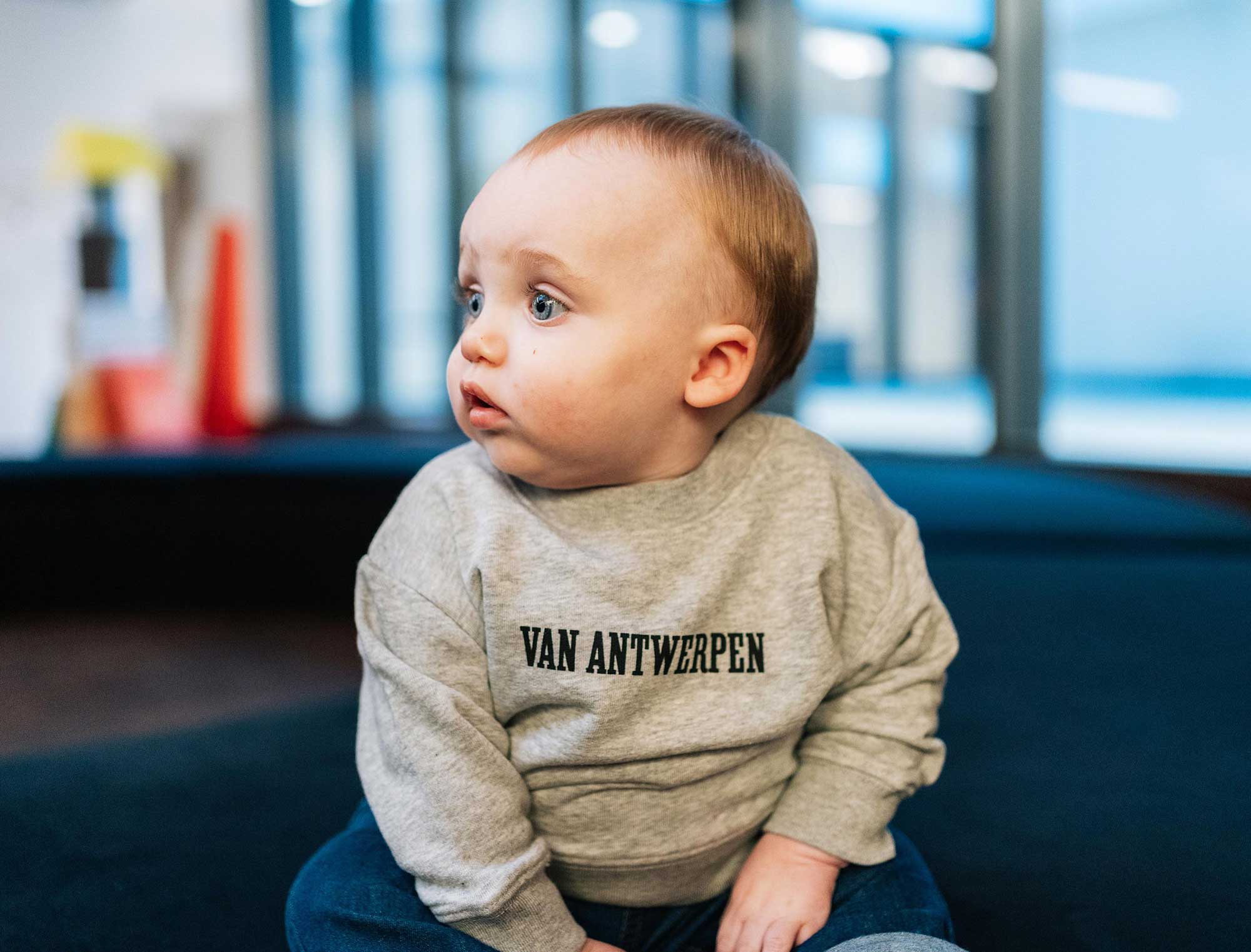 baby met grijze sweater met opdruk Van Antwerpen