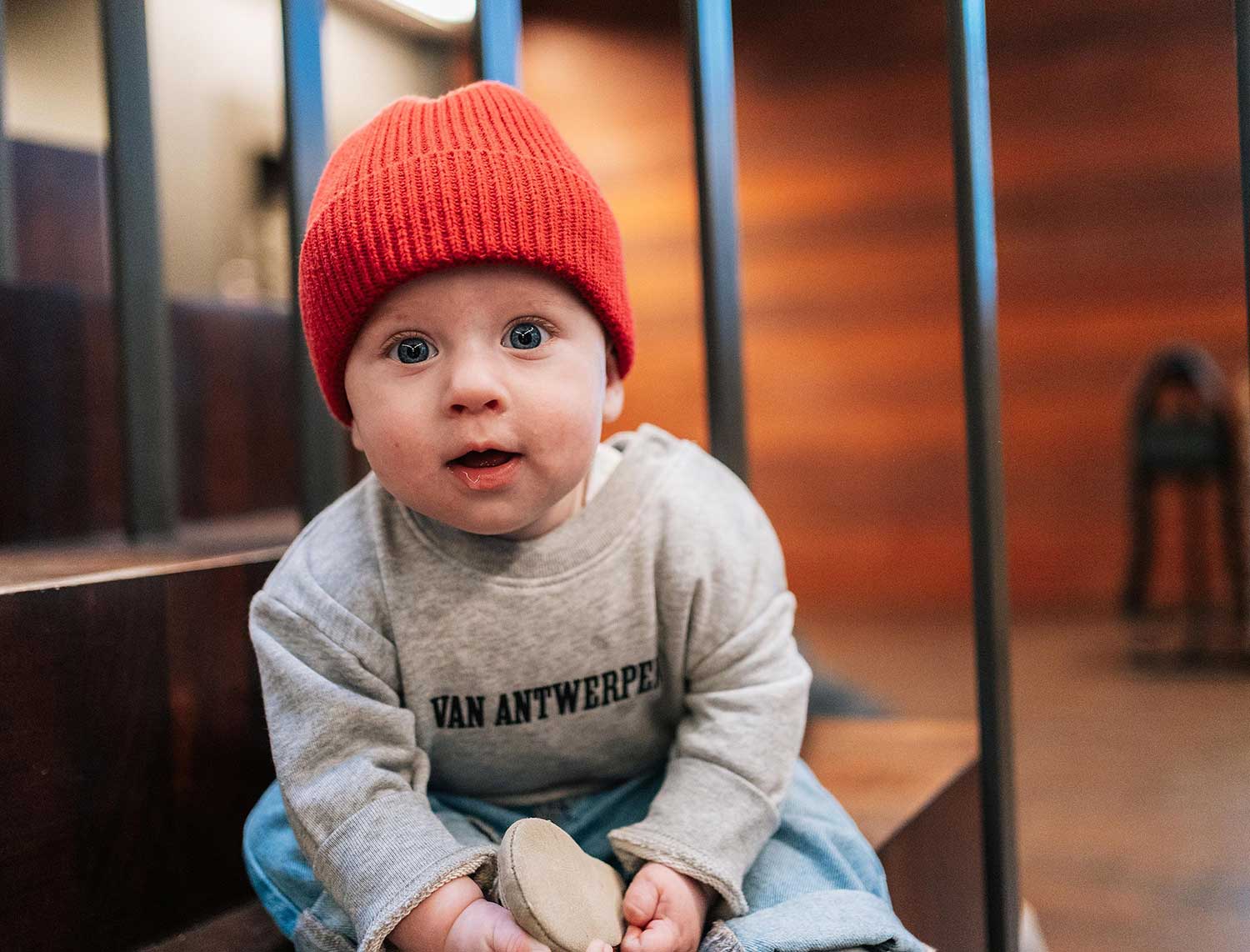 baby met een grijze trui met opdruk Van Antwerpen