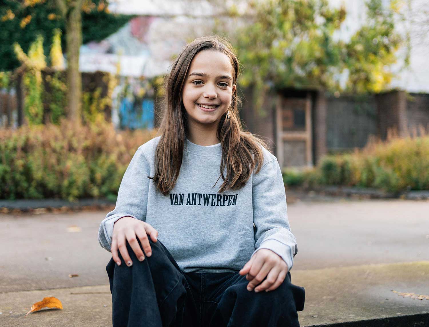 Meisje met een grijze sweater met opdruk Van Antwerpen met typische GVA letters
