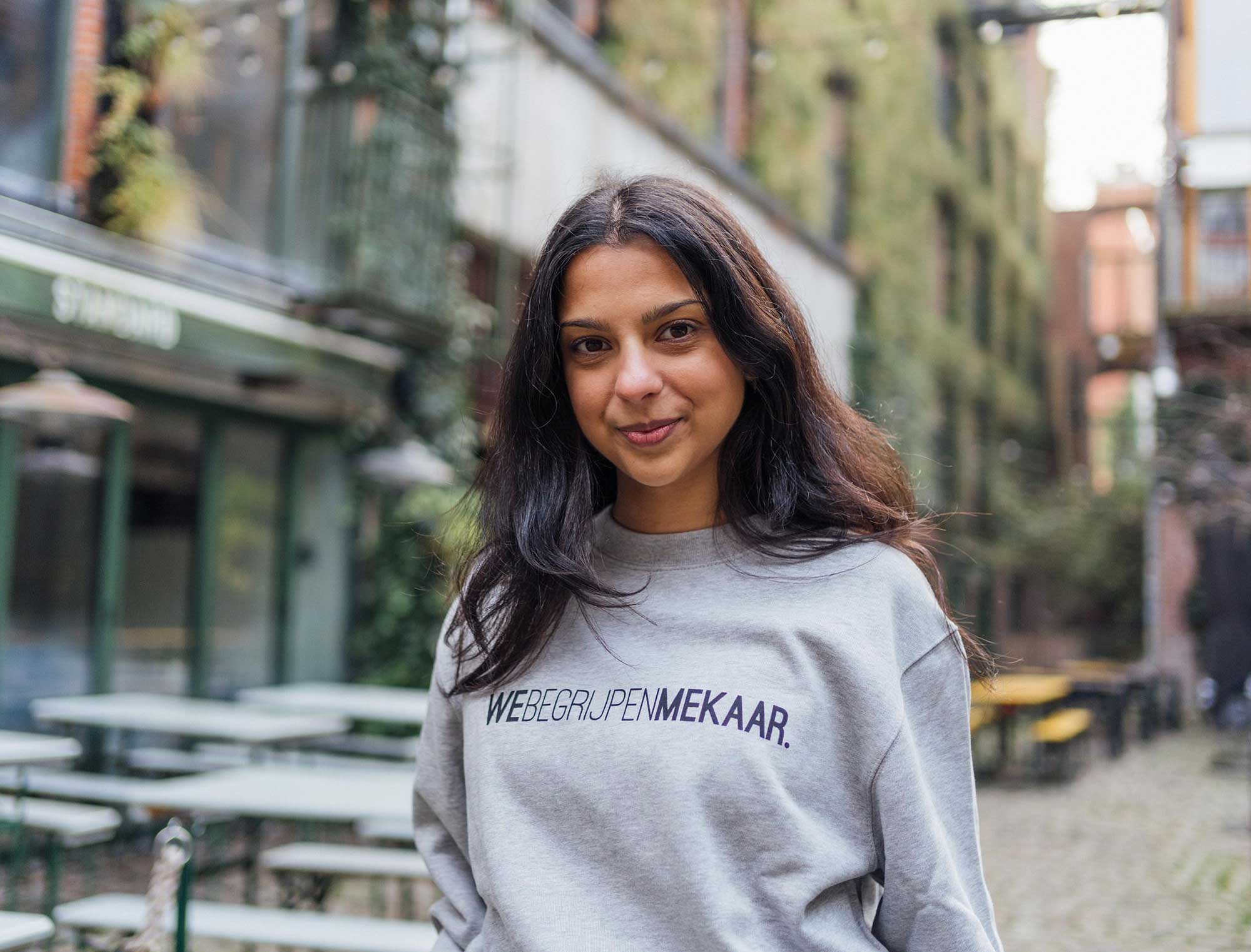 Vrouw met een grijze sweater met opdruk WEBEGRIJPENMEKAAR.