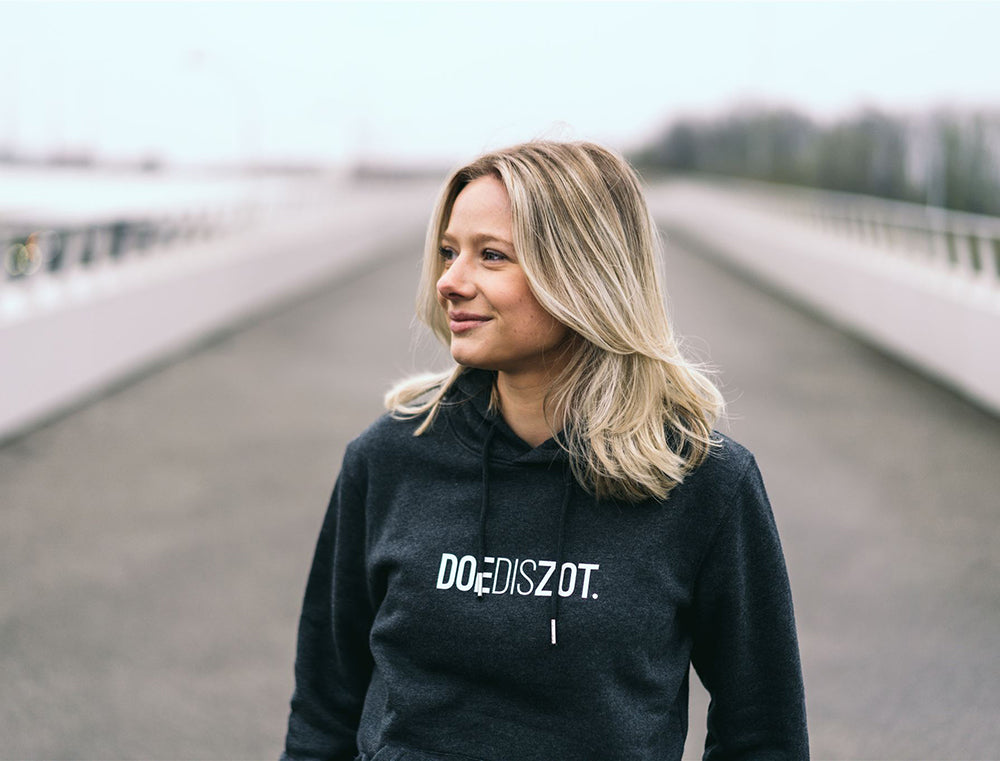 Vrouw met grijze hoodie met opdruk DOEDISZOT.