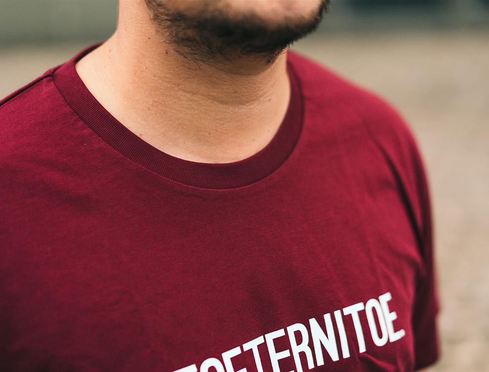 Close-up van bordeaux T-shirt met opdruk TOETERNITOE.