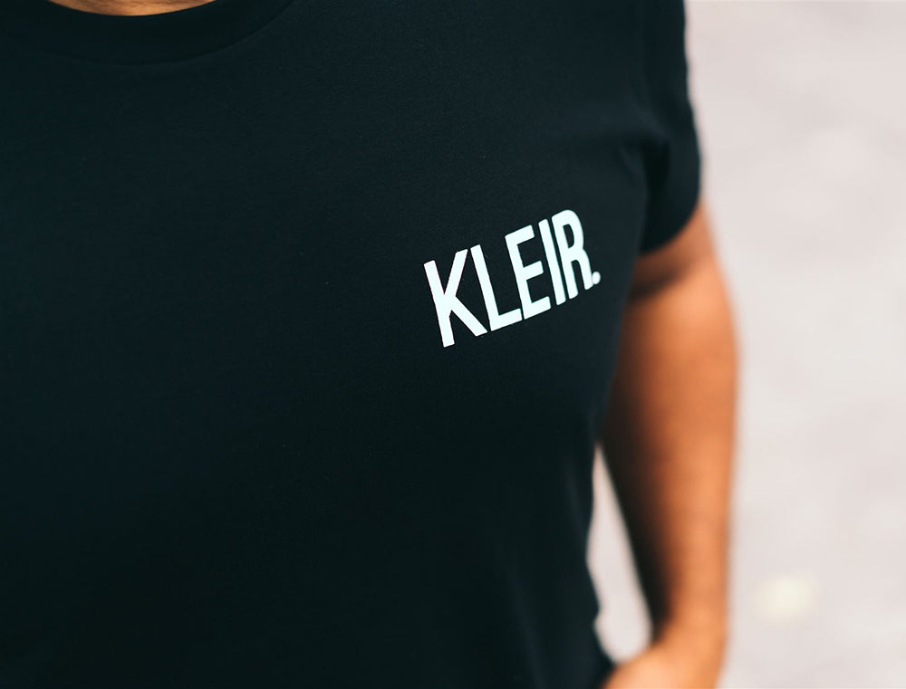 Close-up van een zwarte T-shirt met opschrift KLEIR.