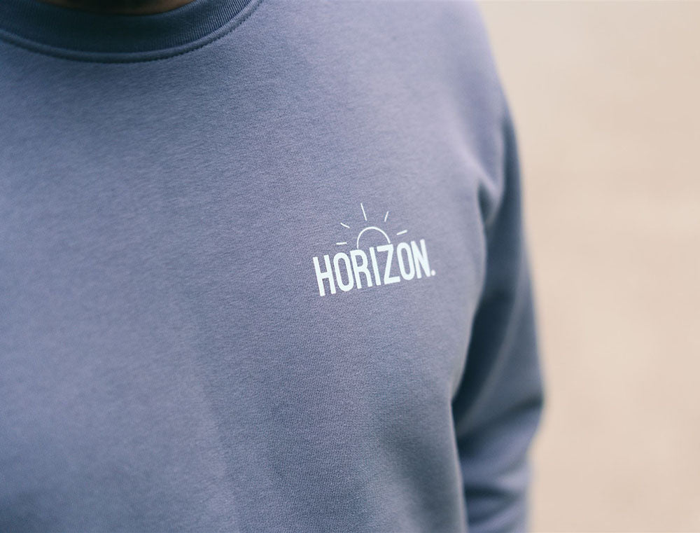 Close-up van de opdruk HORIZON. op een grijze trui.