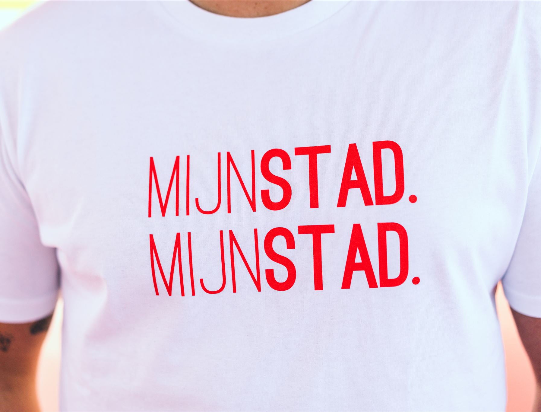 Close-up van een witte T-shirt met rode opdruk MIJNSTAD. MIJNSTAD.