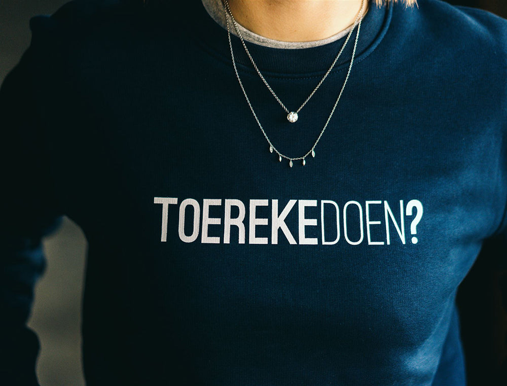 Vrouw met blauwe trui met opdruk TOEREKEDOEN?