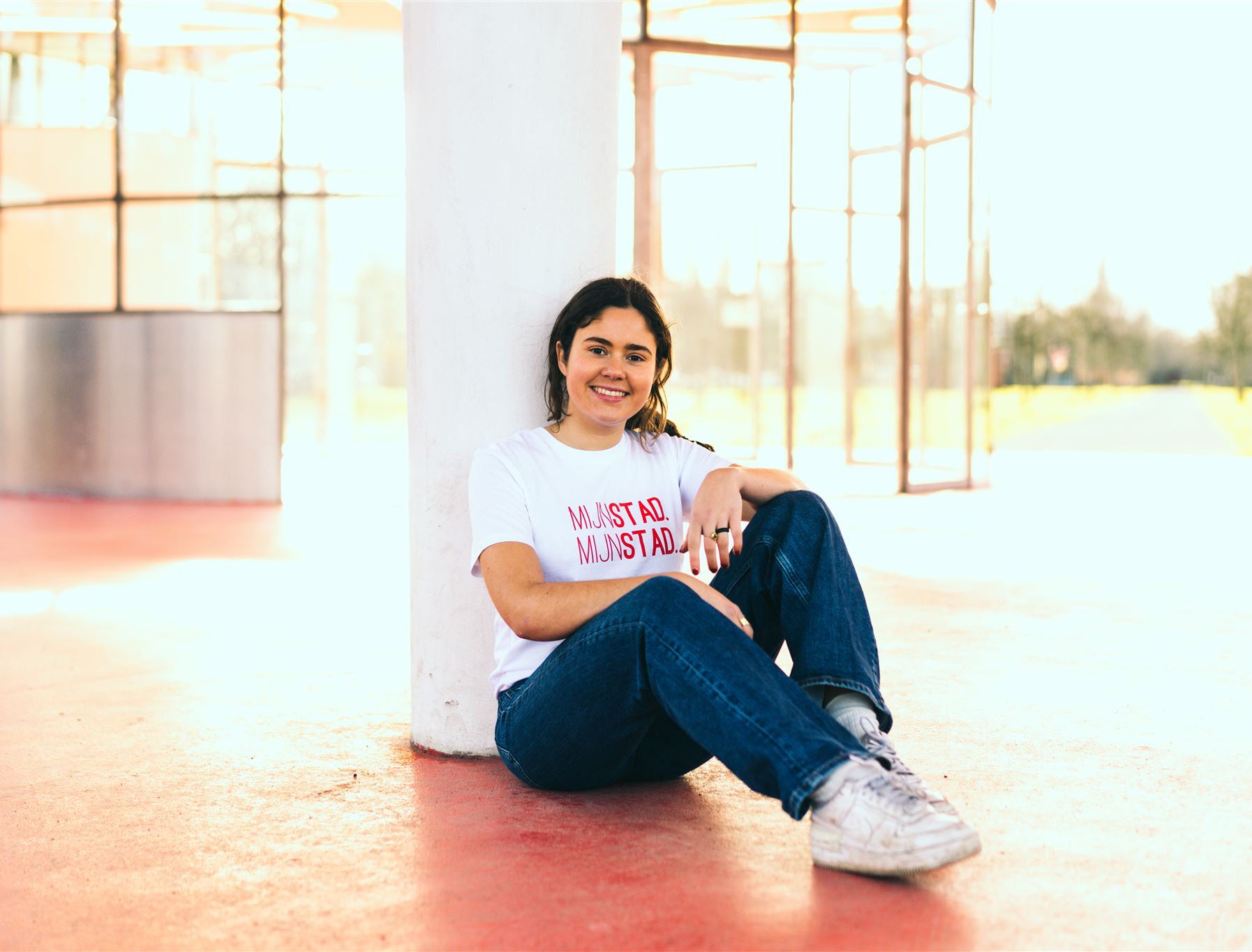 Vrouw met een witte T-shirt met rode opdruk MIJNSTAD. MIJNSTAD.