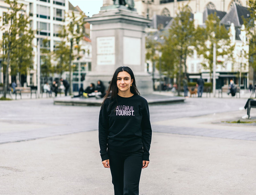Vrouw met zwarte trui met opdruk 'ALLEMAALTOURIST.'