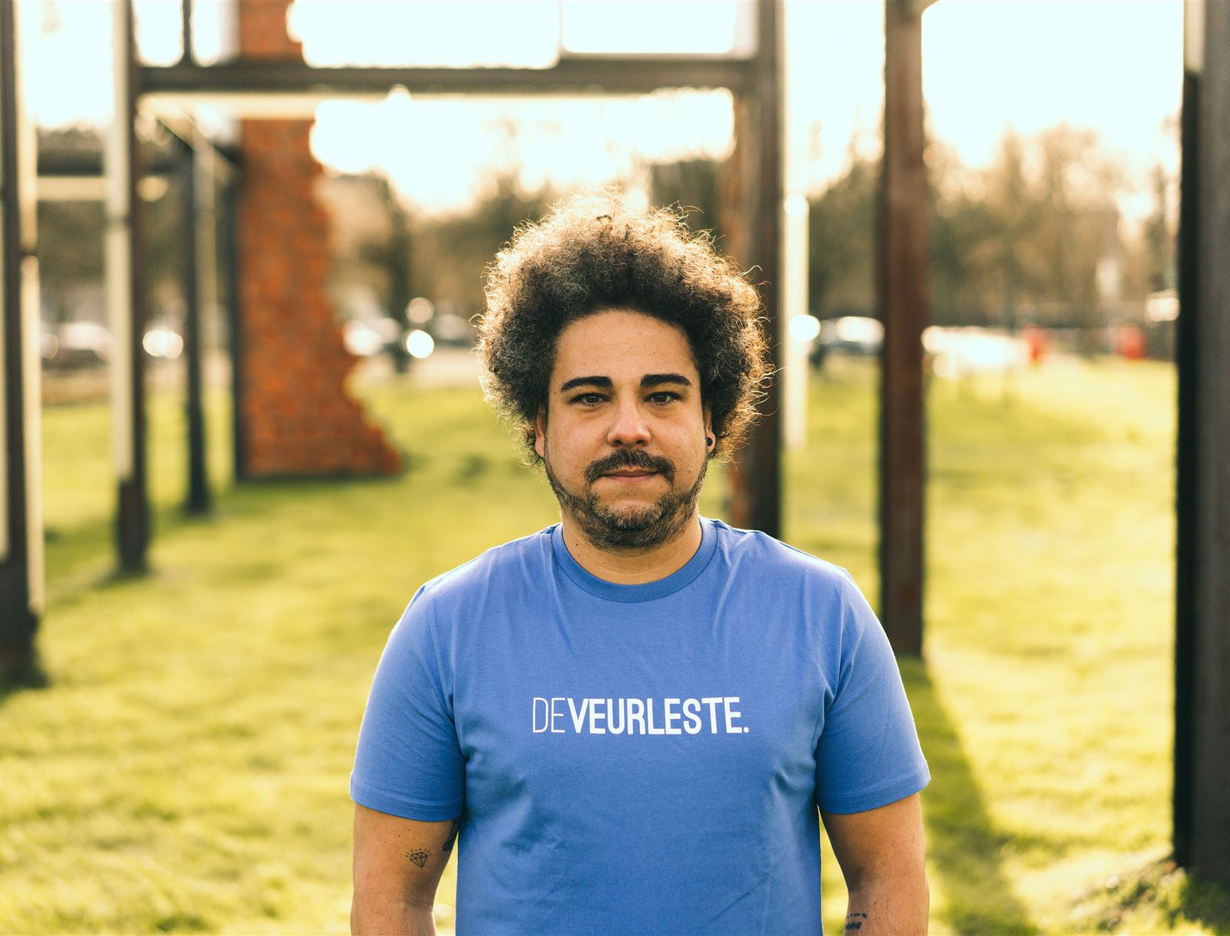 Man met een blauwe T-shirt met opdruk DEVEURLESTE.