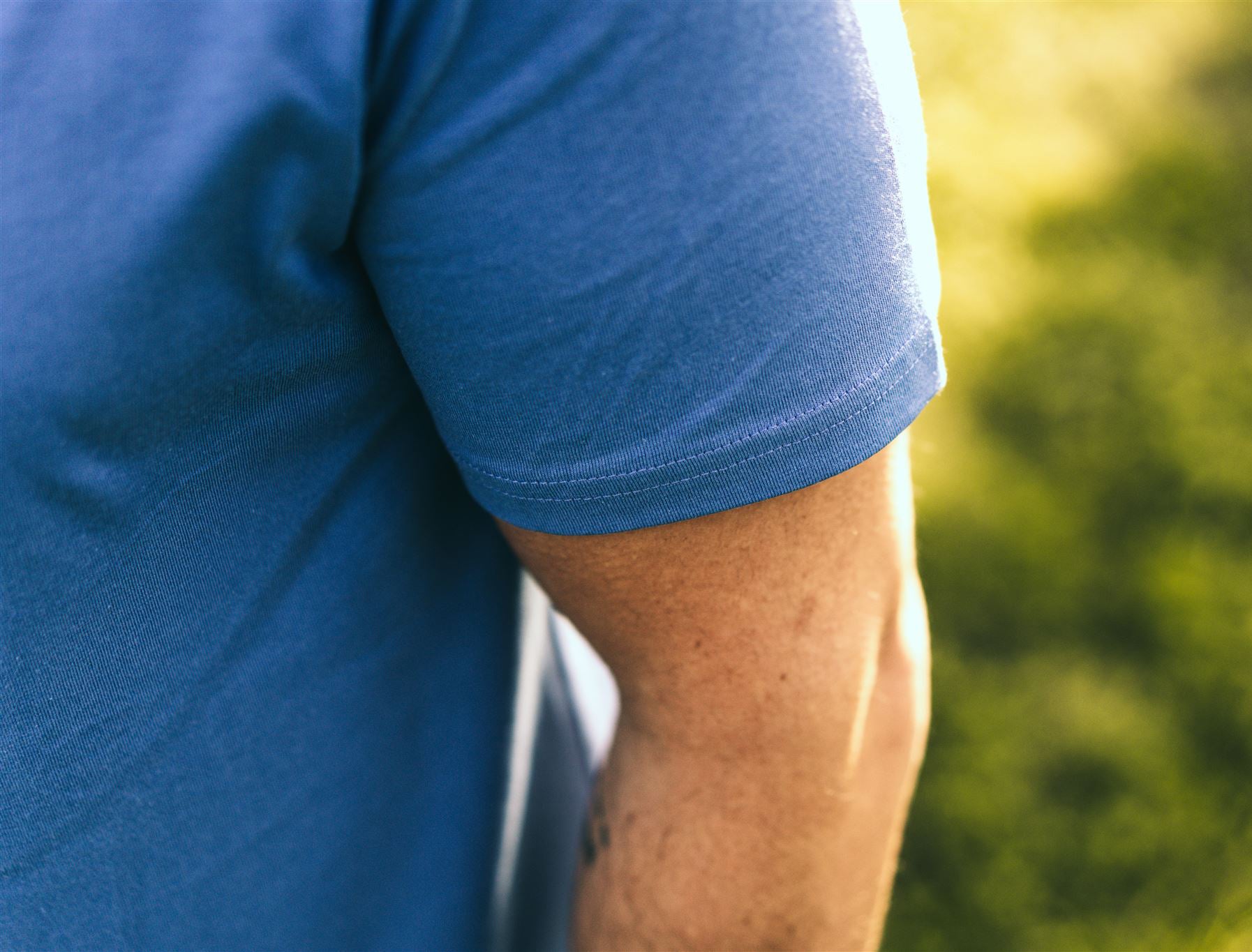 Close-up van een blauwe mouw van een T-shirt.