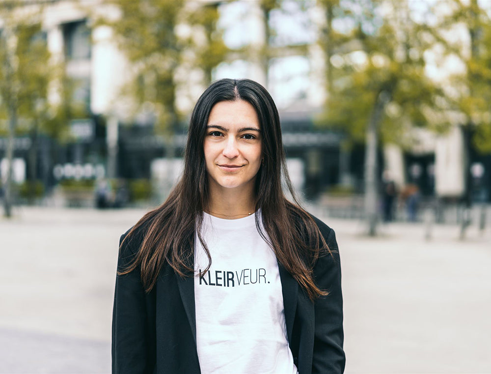 Vrouw met witte T-shirt met opdruk 'KLEIRVEUR.'