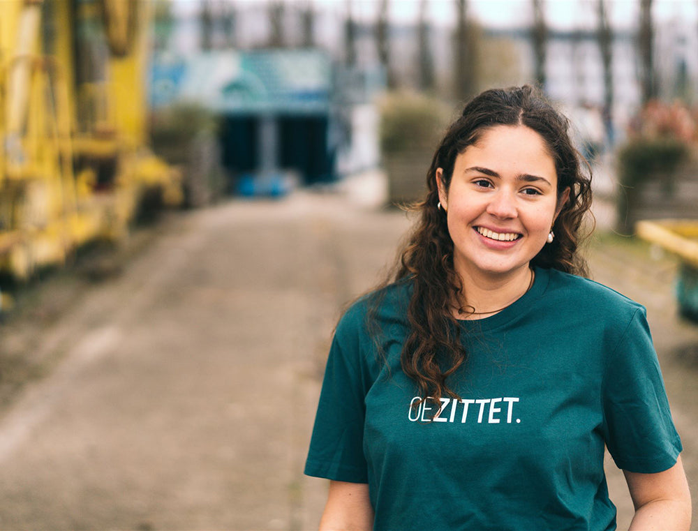 Vrouw met petrolblauwe T-shirt met opdruk OEZITTET.