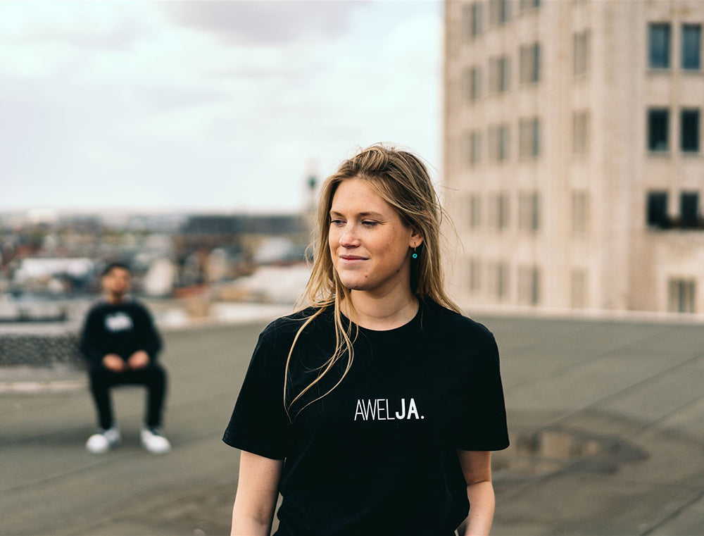 Vrouw met zwarte T-shirt met opdruk 'AWELJA.'