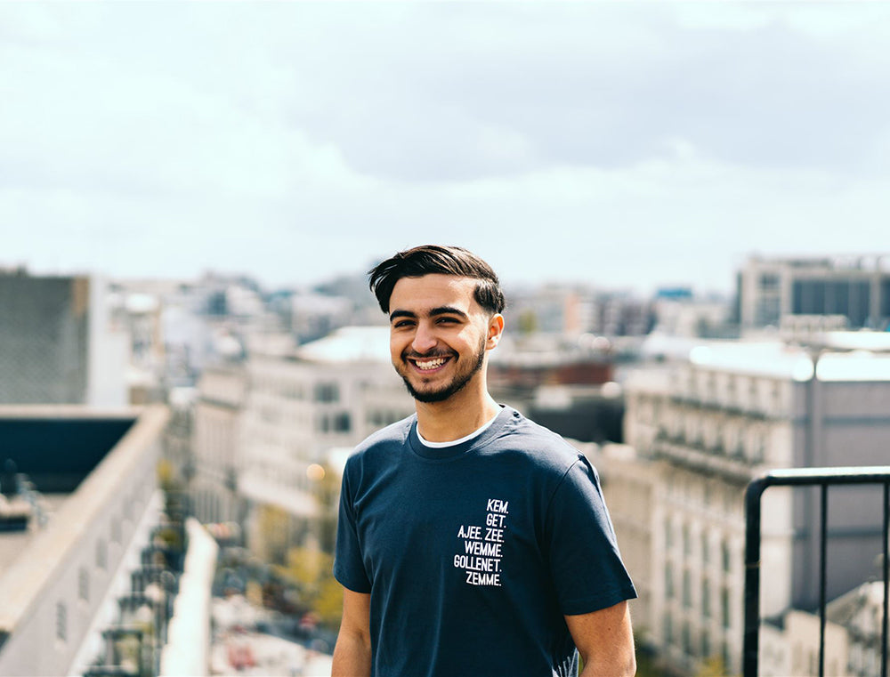 Man met grijze T-shirt met de vervoeging van 'hebben' als opdruk.