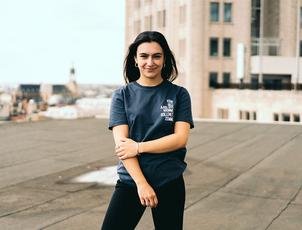 Vrouw met grijze T-shirt met de vervoeging van 'hebben' als opdruk.