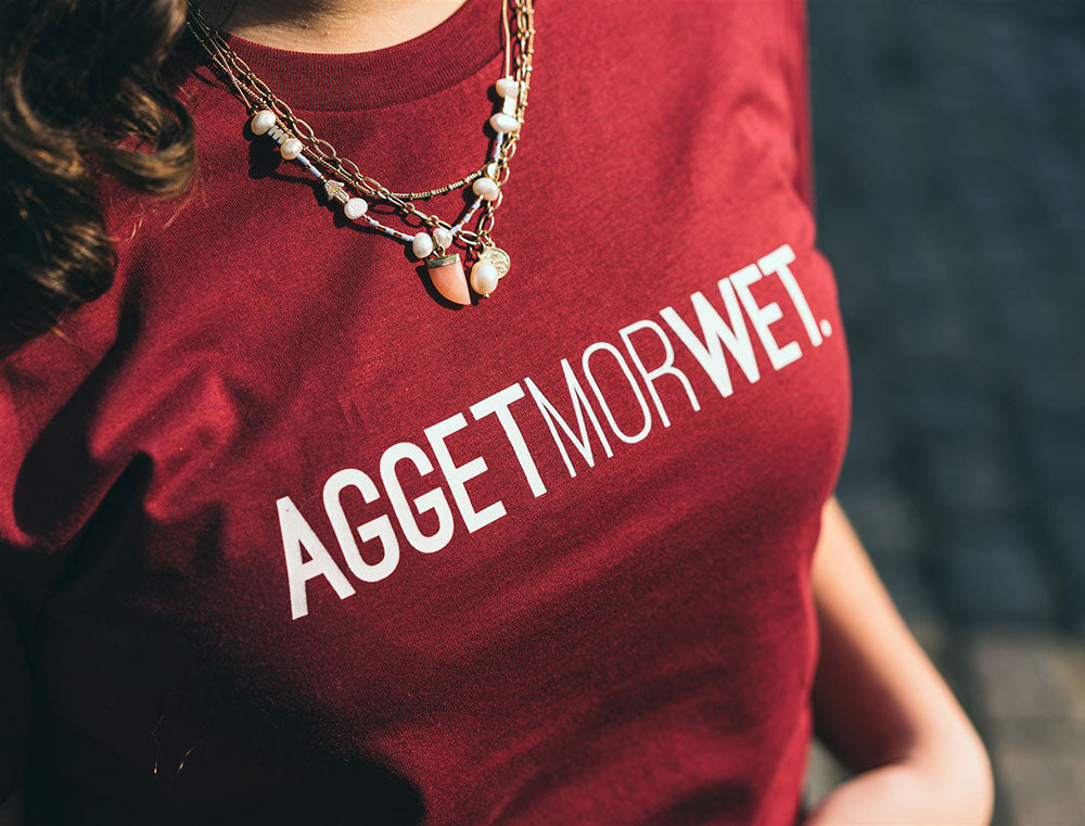 Close-up van T-shirt met opdruk 'AGGETMORWET'.