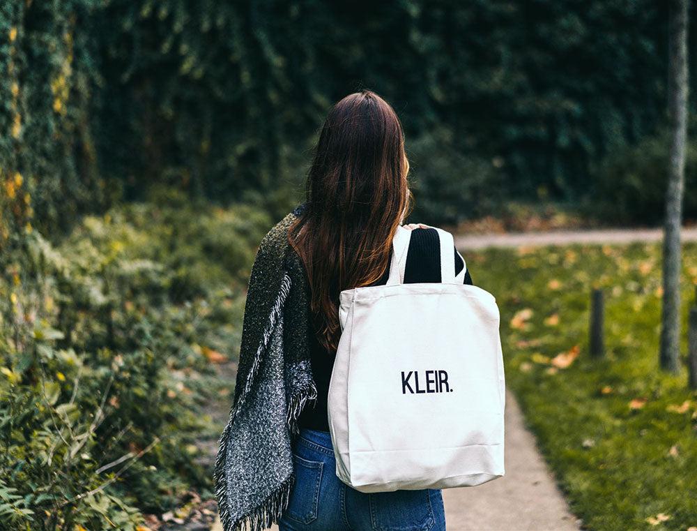 Vrouw met totebag met opdruk KLEIR.