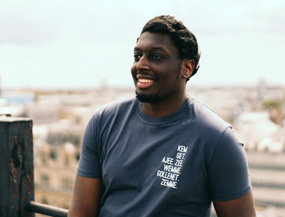 Man met grijze T-shirt met de vervoeging van 'hebben' als opdruk.