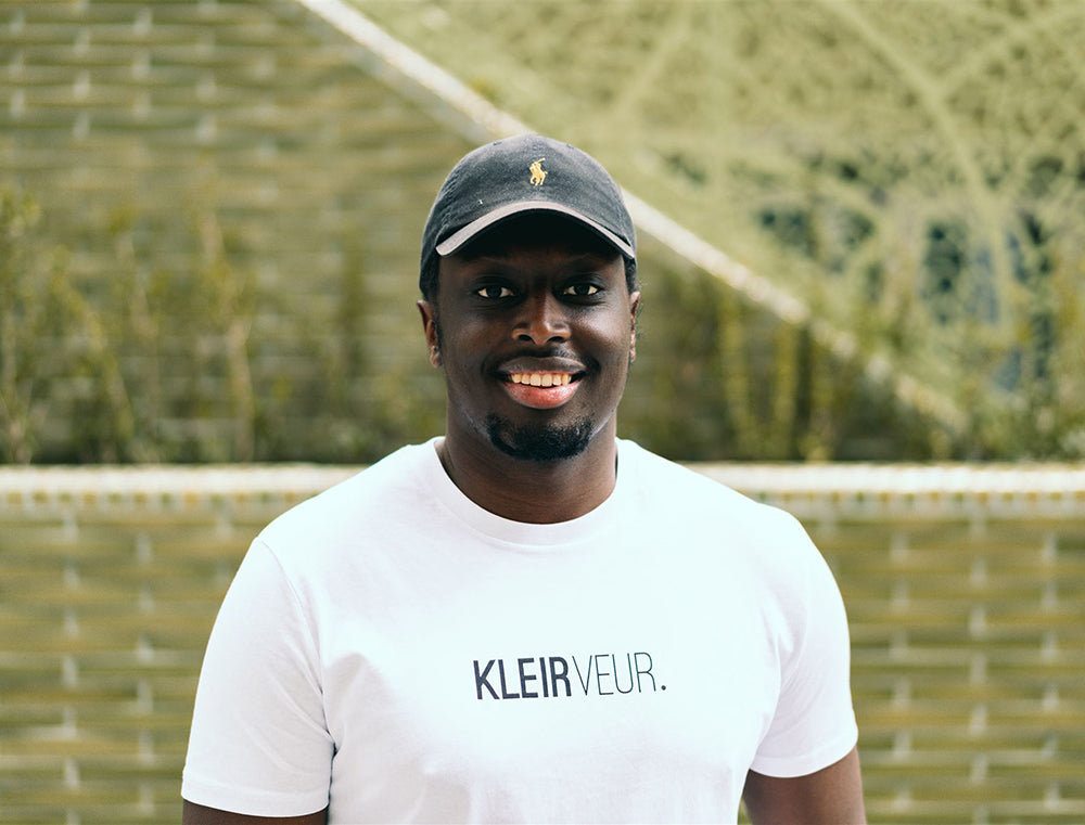 Man met witte T-shirt met opdruk 'KLEIRVEUR.'