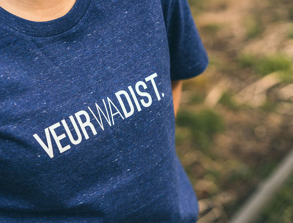 Close-up van blauwe T-shirt met opdruk VEURWADIST.