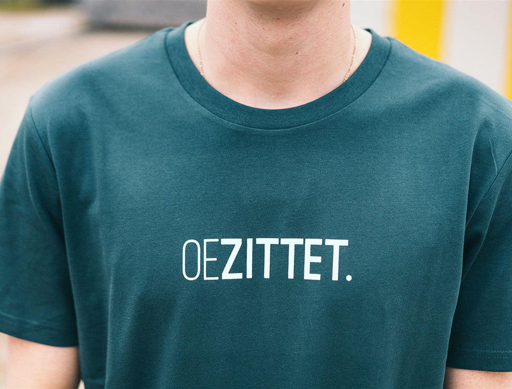 Man met petrolblauwe T-shirt met opdruk OEZITTET.