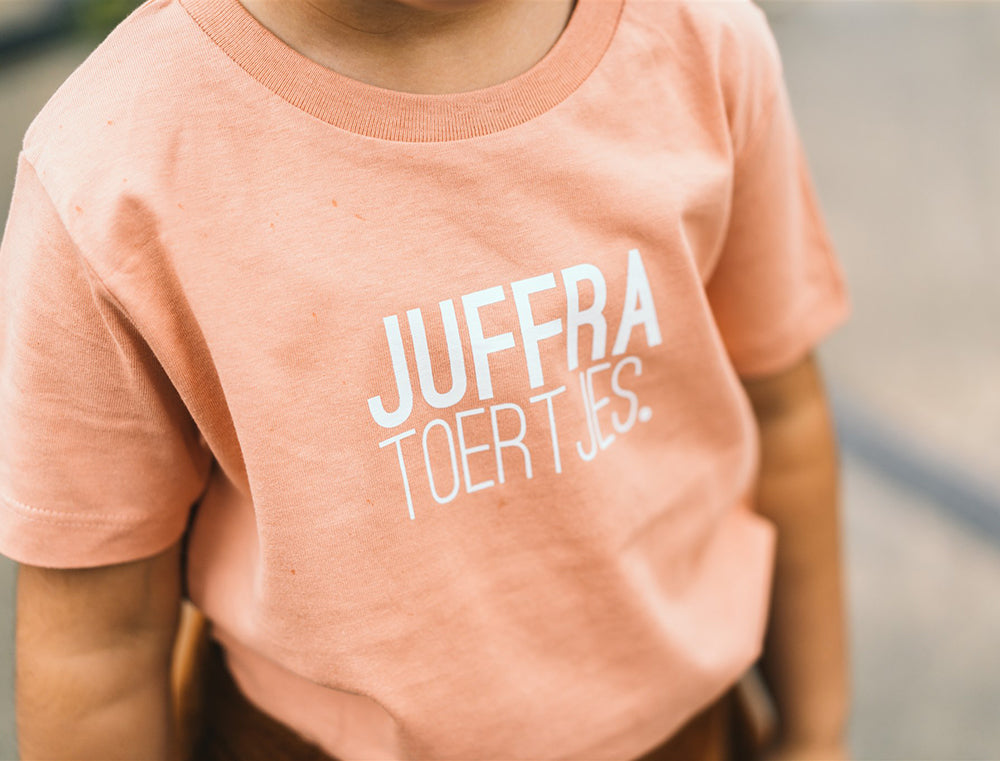 Close-up van roze T-shirt met opdruk JUFFRA TOERTJES.