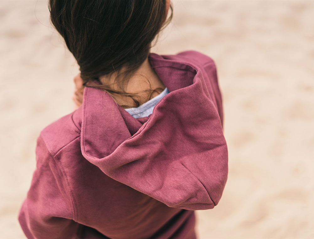 Close-up van een kap van een bordeaux hoodie.