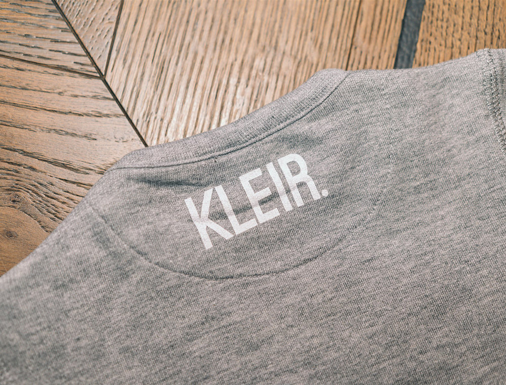 Close-up van grijze trui met logo KLEIR. in de nek