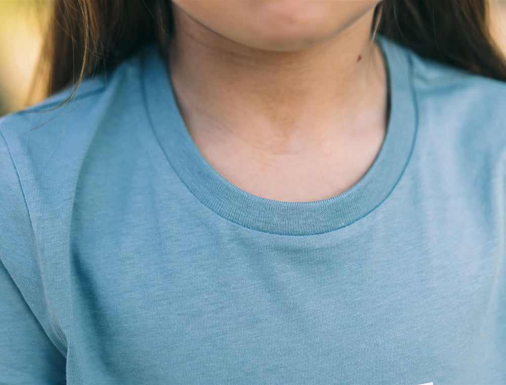 Close-up van een lichtblauwe T-shirt.