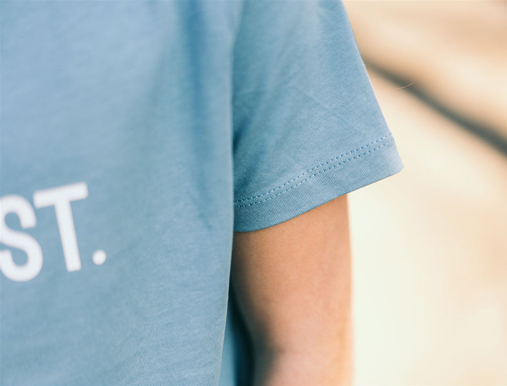 Close-up van een lichtblauwe mouw van een T-shirt.