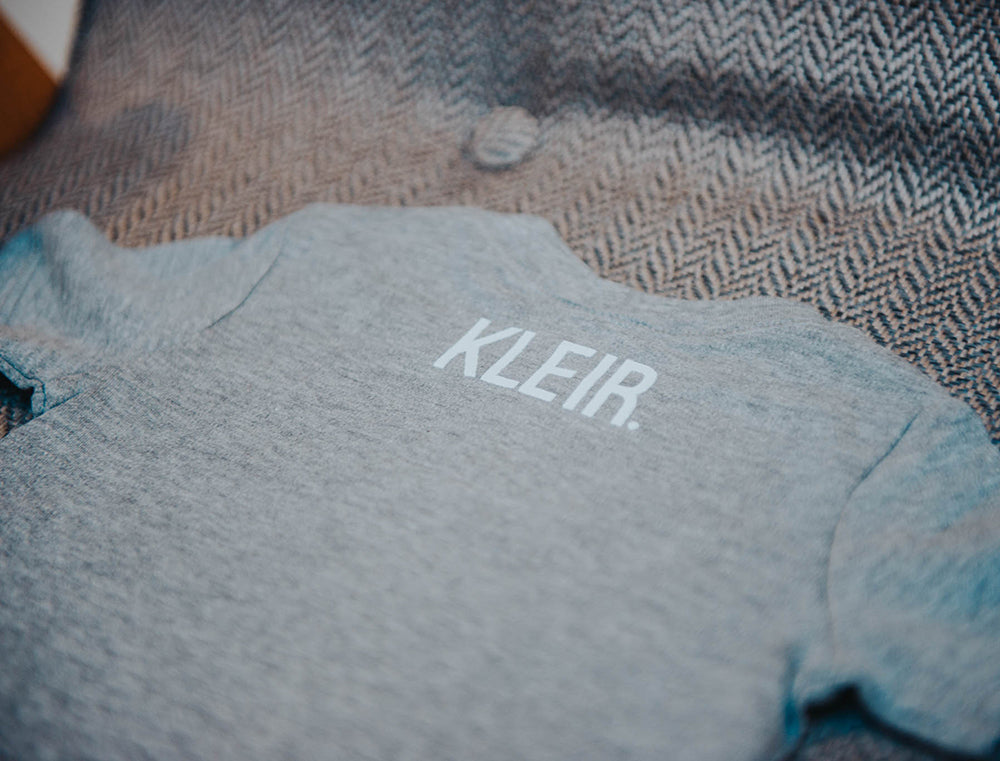 Close-up van grijze baby T-shirt met opdruk KLEIR. in de nek.