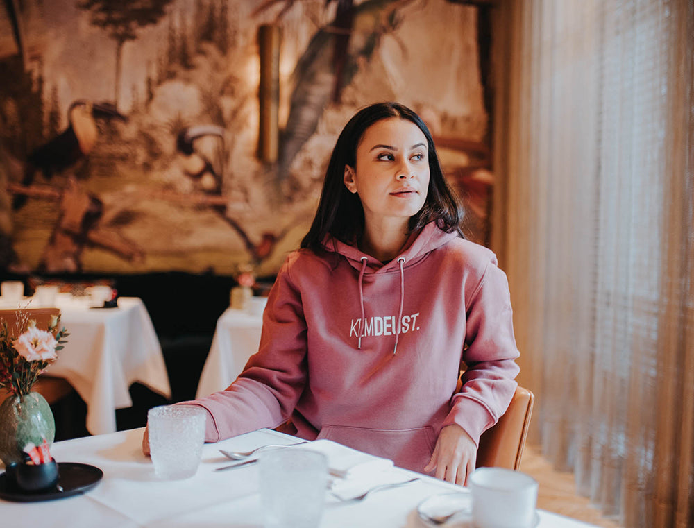 Vrouw met een bordeaux hoodie met opdruk KEMDEUST.