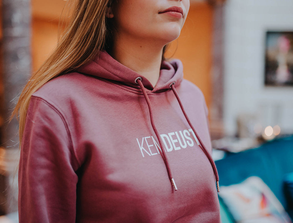Close-up van een bordeaux hoodie met opdruk KEMDEUST.
