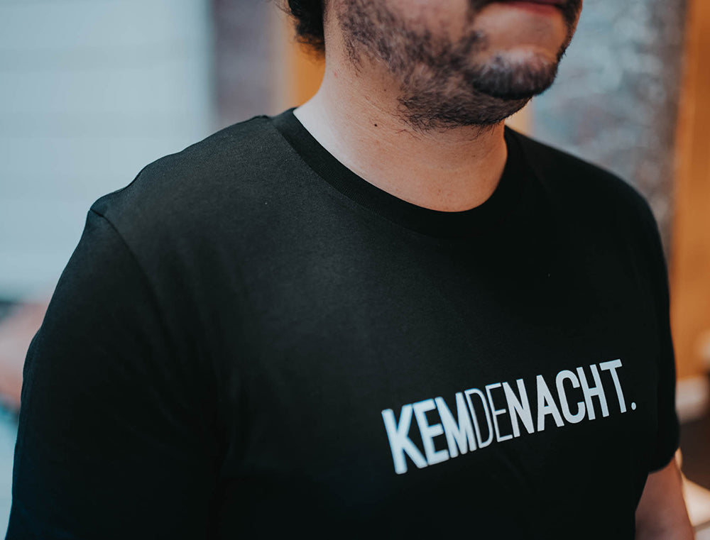 Close-up van een zwarte T-shirt met opdruk KEMDENACHT.