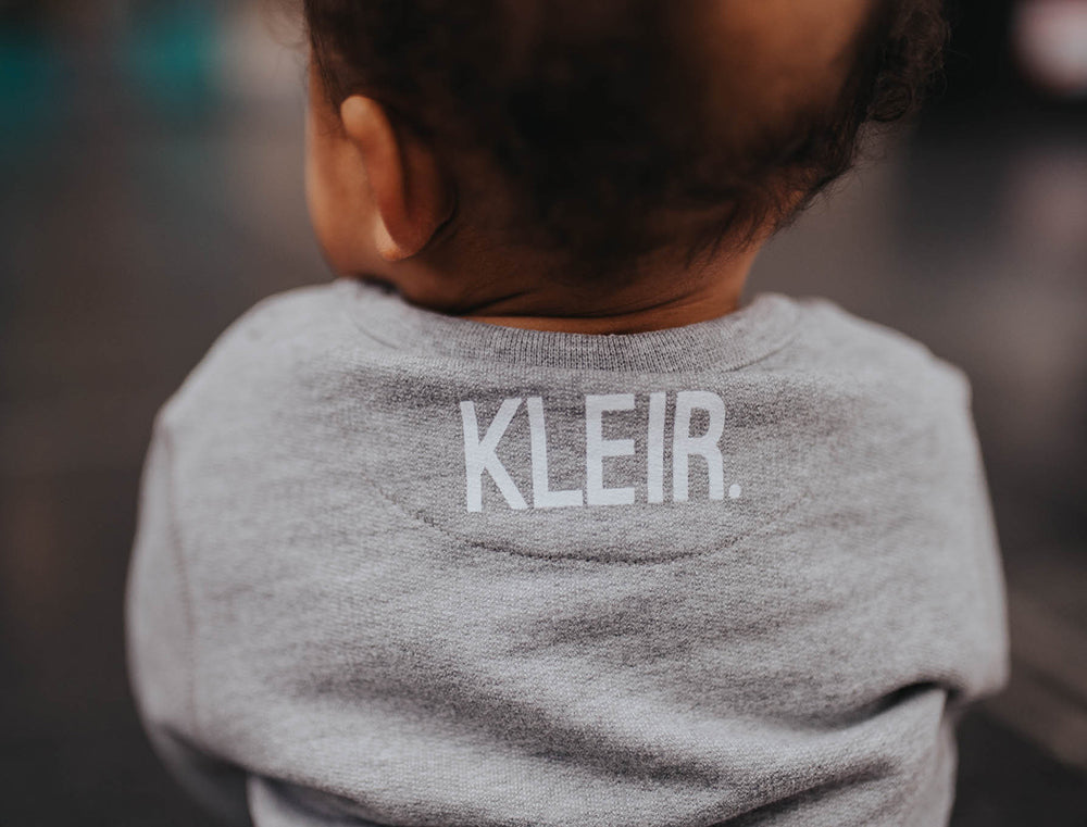 Close-up van een grijze baby T-shirt met het KLEIR. logo