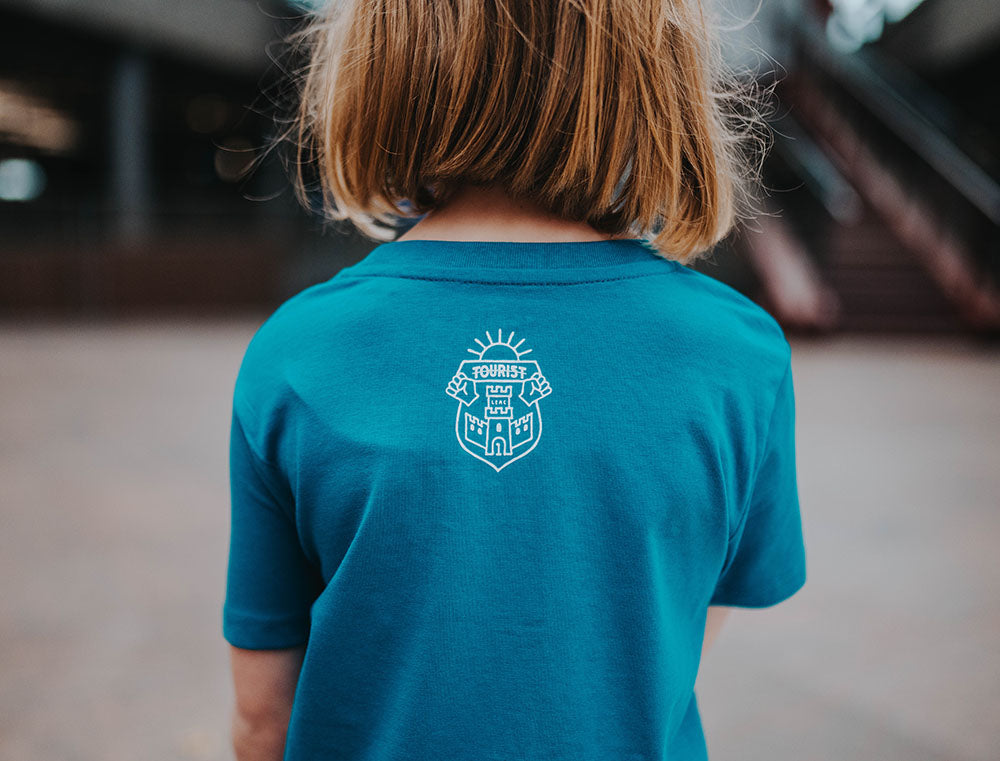 Close-up van het logo van Tourist op een blauwe T-shirt